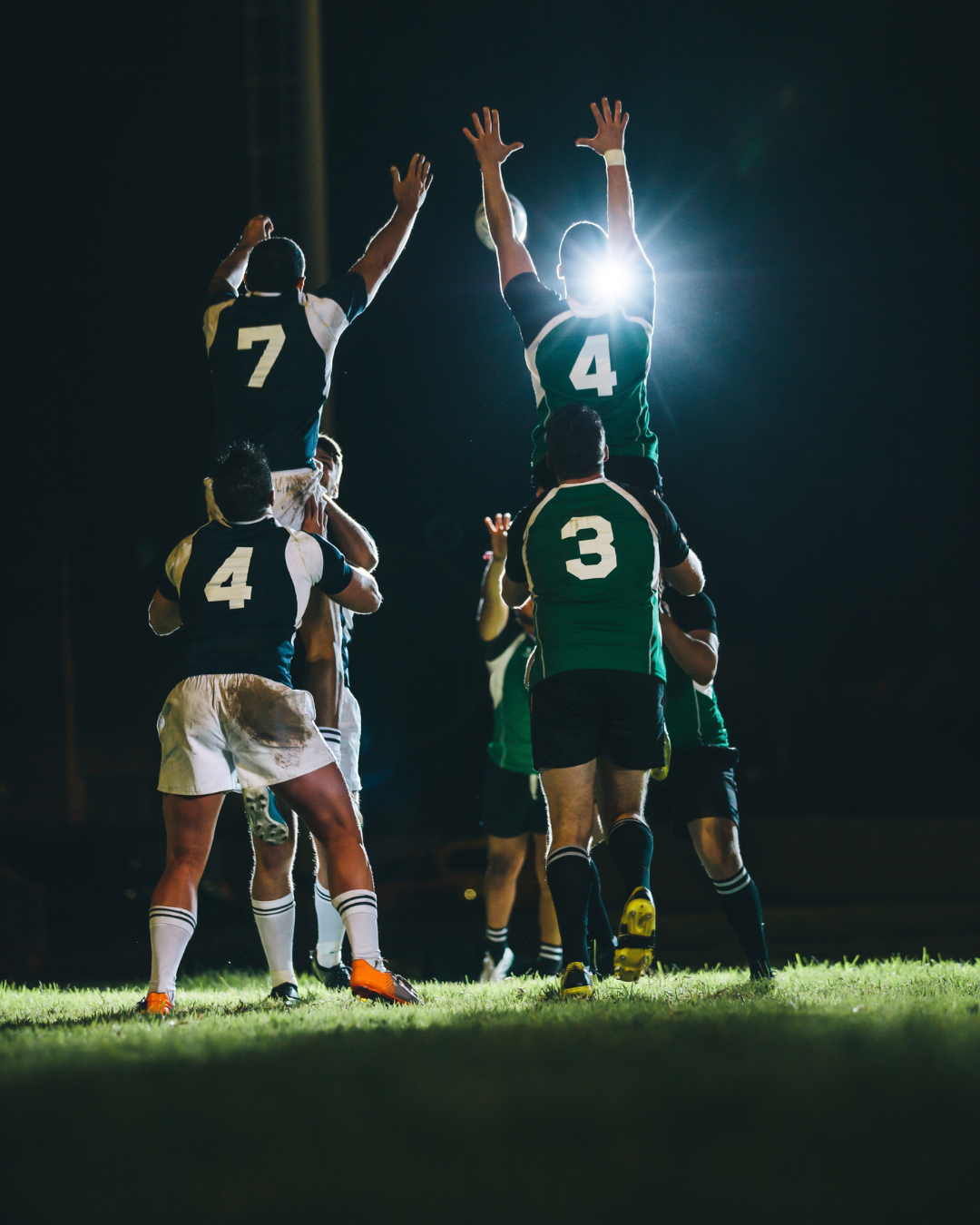 Rugby players reaching for the ball together